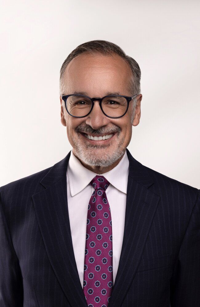 Smiling man in suit with glasses and tie.