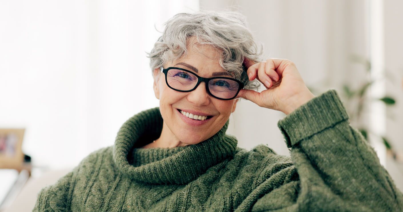 Smiling older woman in cozy green sweater.