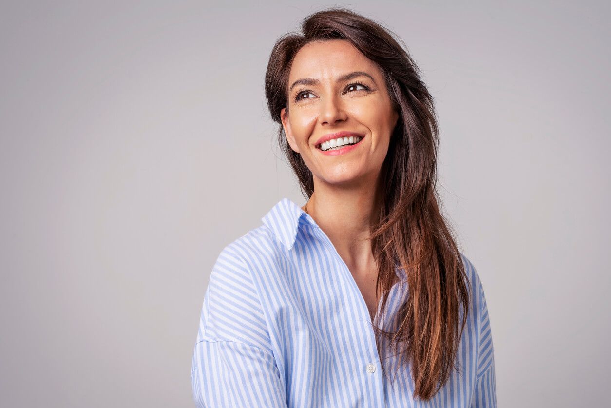 Smiling woman in a striped shirt, neutral background.