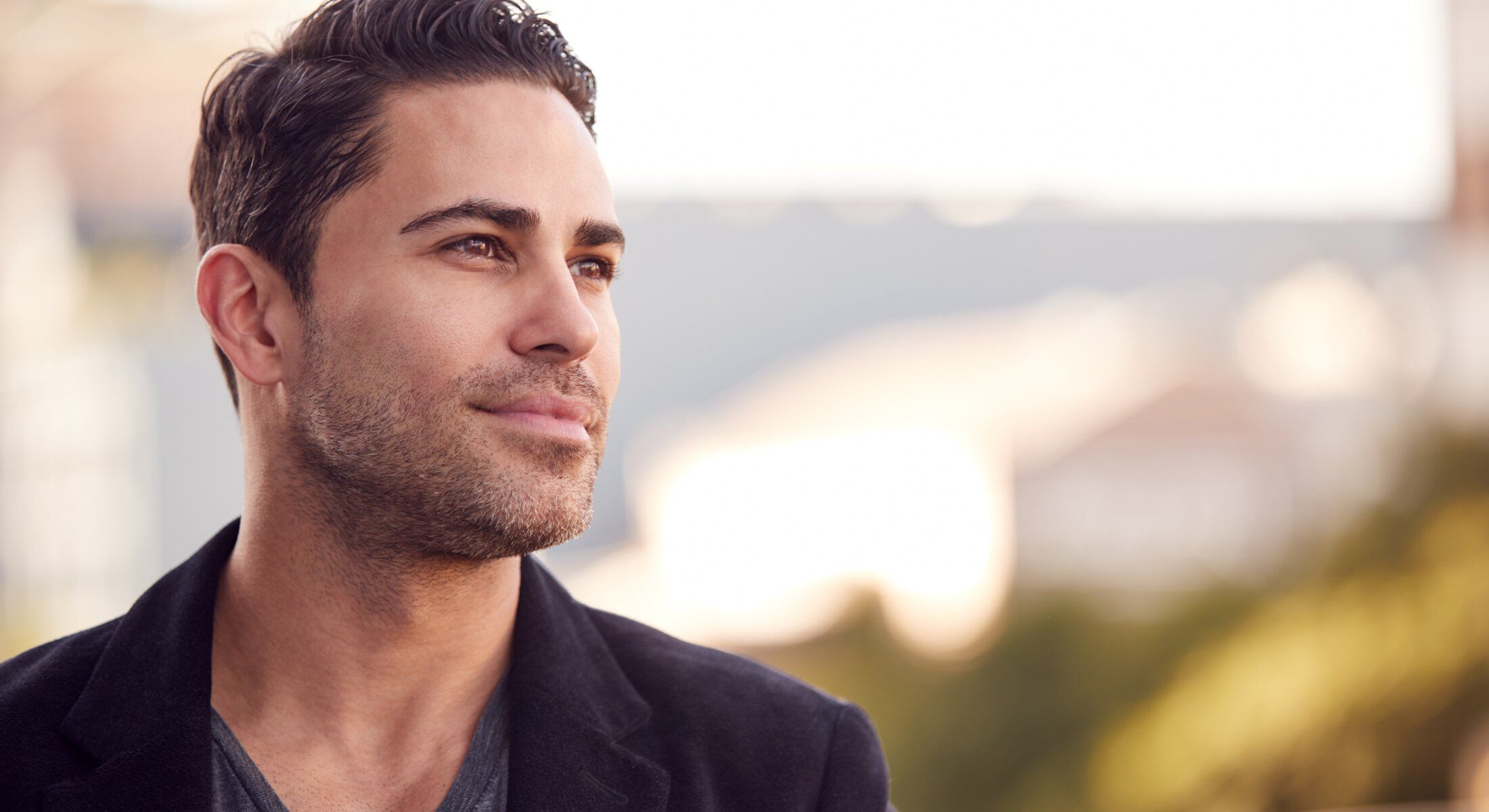 Man looking thoughtfully into the distance outdoors.