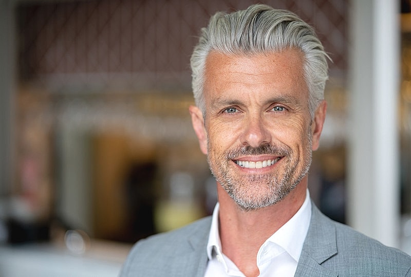 Smiling man with gray hair and suit.