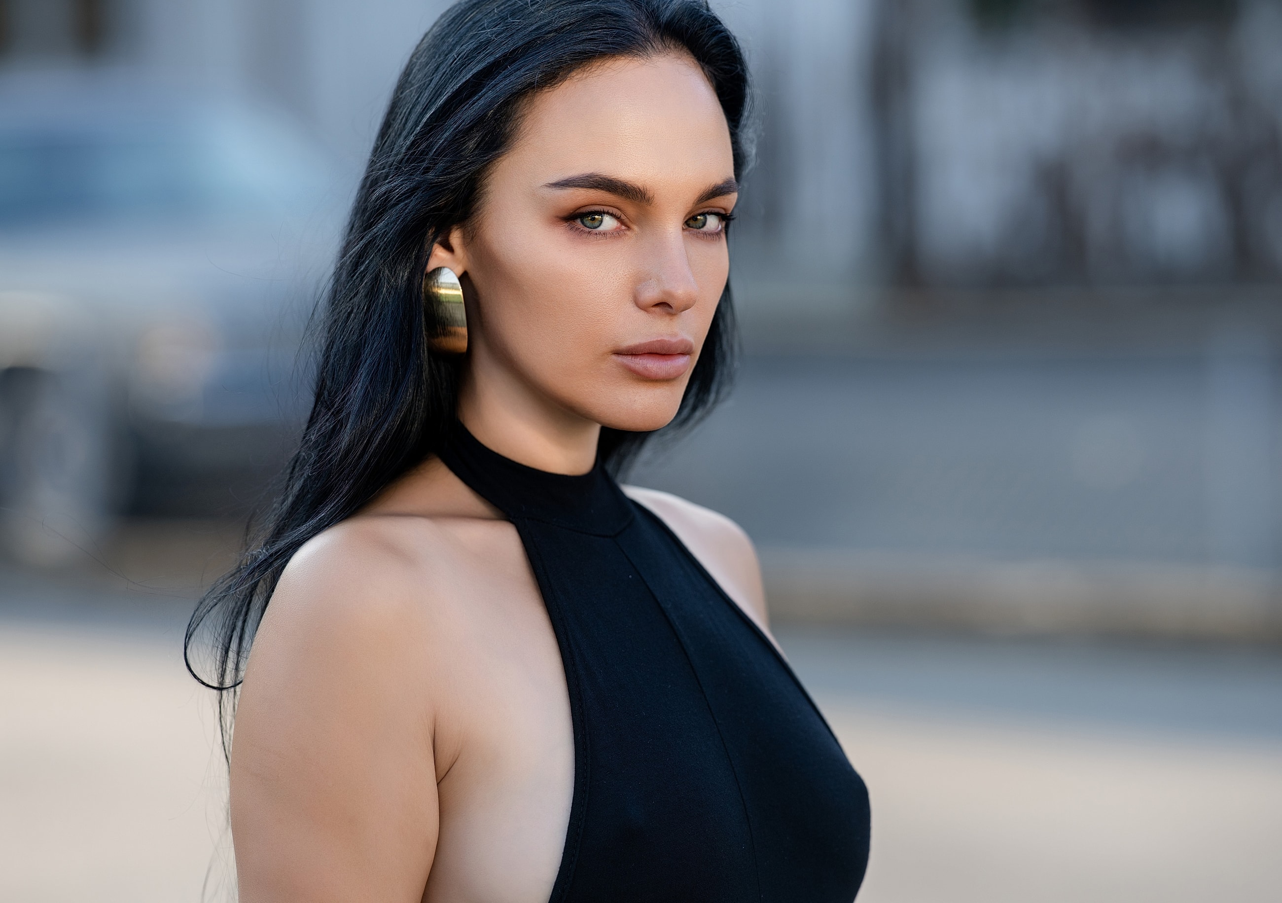 Model in black outfit with hoop earrings.