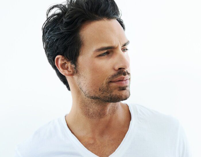 Man in white shirt looking thoughtfully to the side.