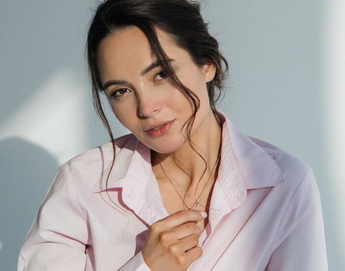 Woman in a pink shirt, softly smiling.
