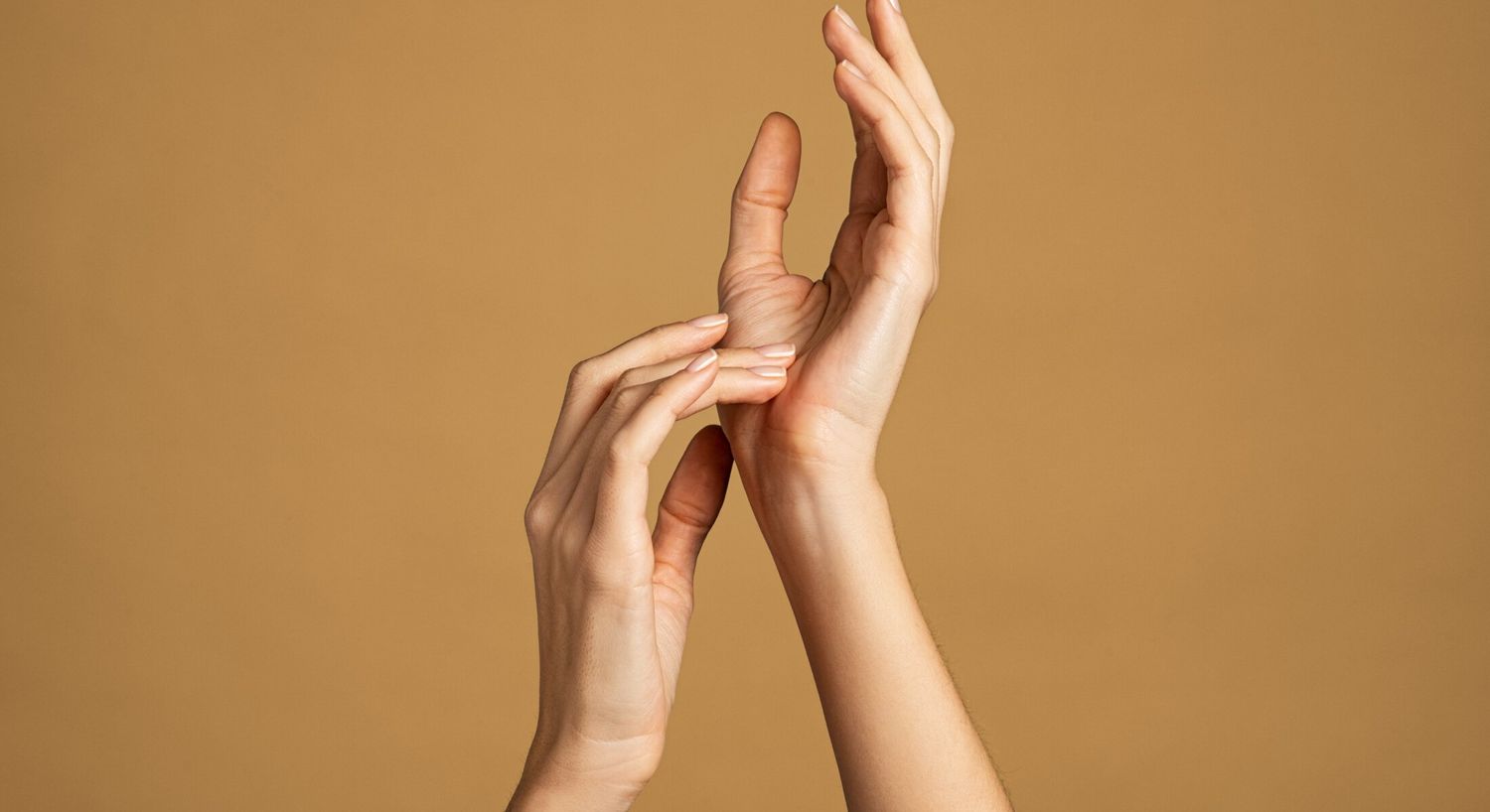 Two hands gracefully touching against a neutral background.