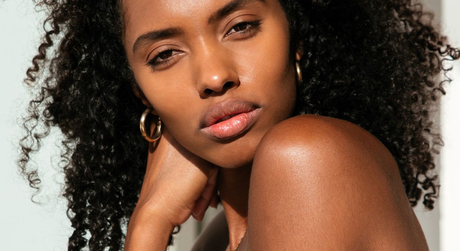 Close-up of woman with curly hair and earrings.