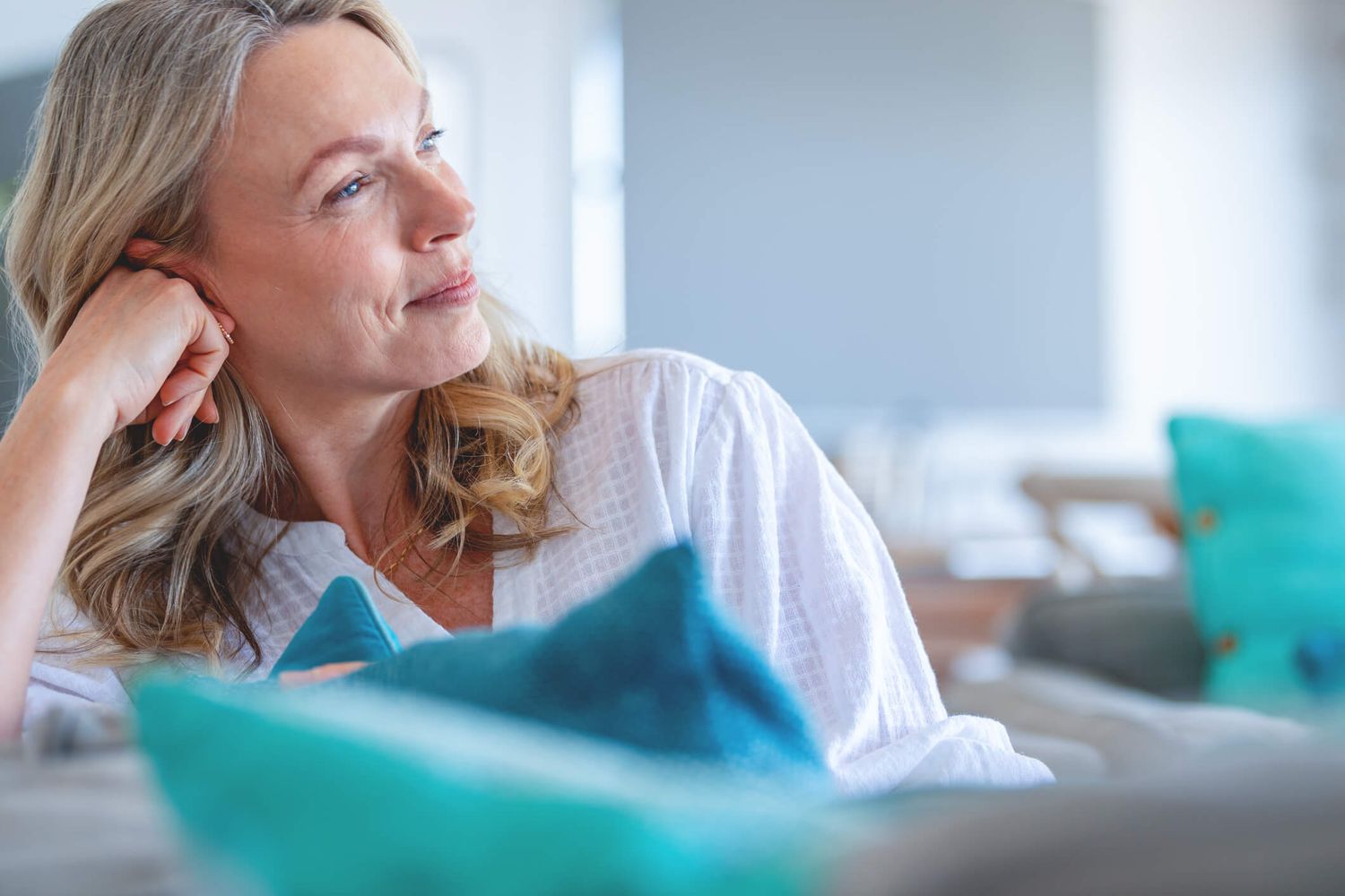 Woman relaxing on couch, looking thoughtfully away.